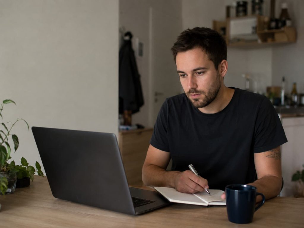 Junger Teilnehmer lernt online für die Security Weiterbildung Duisburg und macht Notizen am Laptop